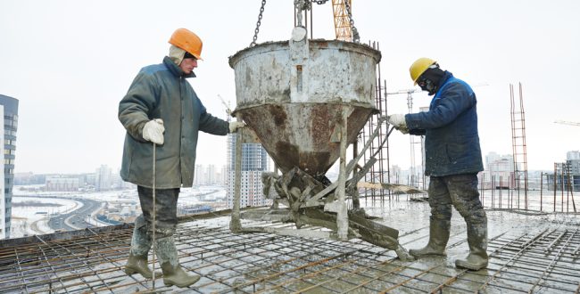 construction building workers at construction site pouring concrete in form